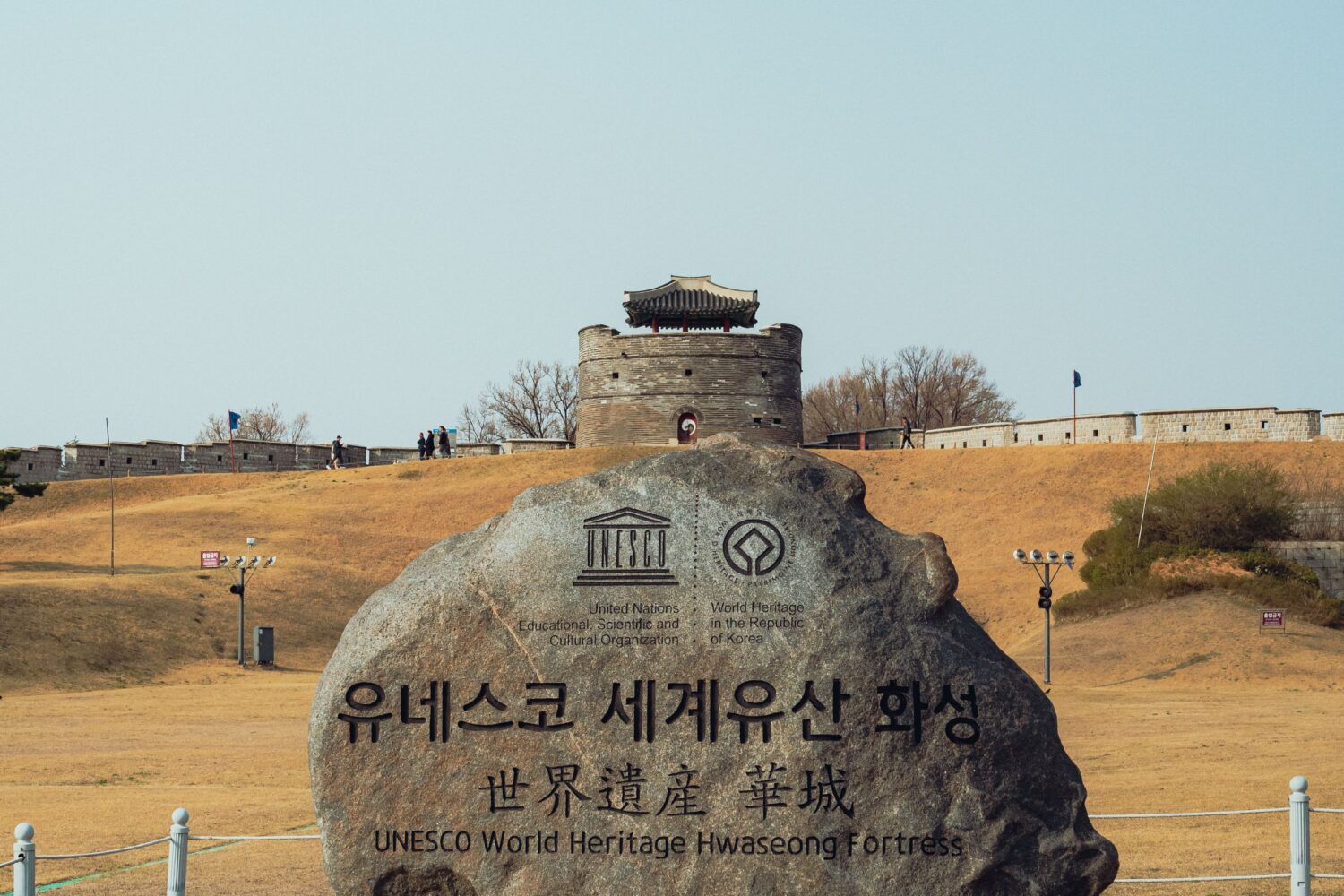 A stone marker indicating the UNESCO World Heritage Site Hwaseong Fortress in Suwon, South Korea.