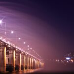 Night view of an illuminated bridge and city skyline, showcasing vibrant lights and urban architecture. 汉江野餐团, 盘浦汉江公园野餐垫, Some Sevit夜景, 彩虹喷泉表演, 便利店美食组合, 반포 한강공원 피크닉 매트, 세빛섬 야경, 무지개 분수 쇼, 편의점 꿀조합 미식, Han River Picnic Tour, Banpo Park picnic mat, Some Sevit night view, Rainbow Fountain show, convenience store spread, 盤浦漢江公園野餐墊, 漢江野餐團, 世貌島夜景, 彩虹噴泉表演, 便利商店美食組合