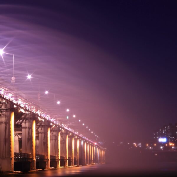 Night view of an illuminated bridge and city skyline, showcasing vibrant lights and urban architecture. 汉江野餐团, 盘浦汉江公园野餐垫, Some Sevit夜景, 彩虹喷泉表演, 便利店美食组合, 반포 한강공원 피크닉 매트, 세빛섬 야경, 무지개 분수 쇼, 편의점 꿀조합 미식, Han River Picnic Tour, Banpo Park picnic mat, Some Sevit night view, Rainbow Fountain show, convenience store spread, 盤浦漢江公園野餐墊, 漢江野餐團, 世貌島夜景, 彩虹噴泉表演, 便利商店美食組合