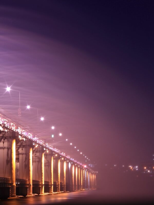 Night view of an illuminated bridge and city skyline, showcasing vibrant lights and urban architecture. 汉江野餐团, 盘浦汉江公园野餐垫, Some Sevit夜景, 彩虹喷泉表演, 便利店美食组合, 반포 한강공원 피크닉 매트, 세빛섬 야경, 무지개 분수 쇼, 편의점 꿀조합 미식, Han River Picnic Tour, Banpo Park picnic mat, Some Sevit night view, Rainbow Fountain show, convenience store spread, 盤浦漢江公園野餐墊, 漢江野餐團, 世貌島夜景, 彩虹噴泉表演, 便利商店美食組合