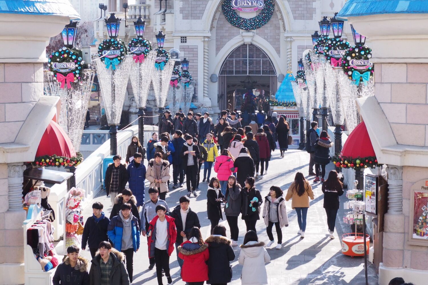People enjoying a winter day at a decorated theme park entrance with festive Christmas decorations.