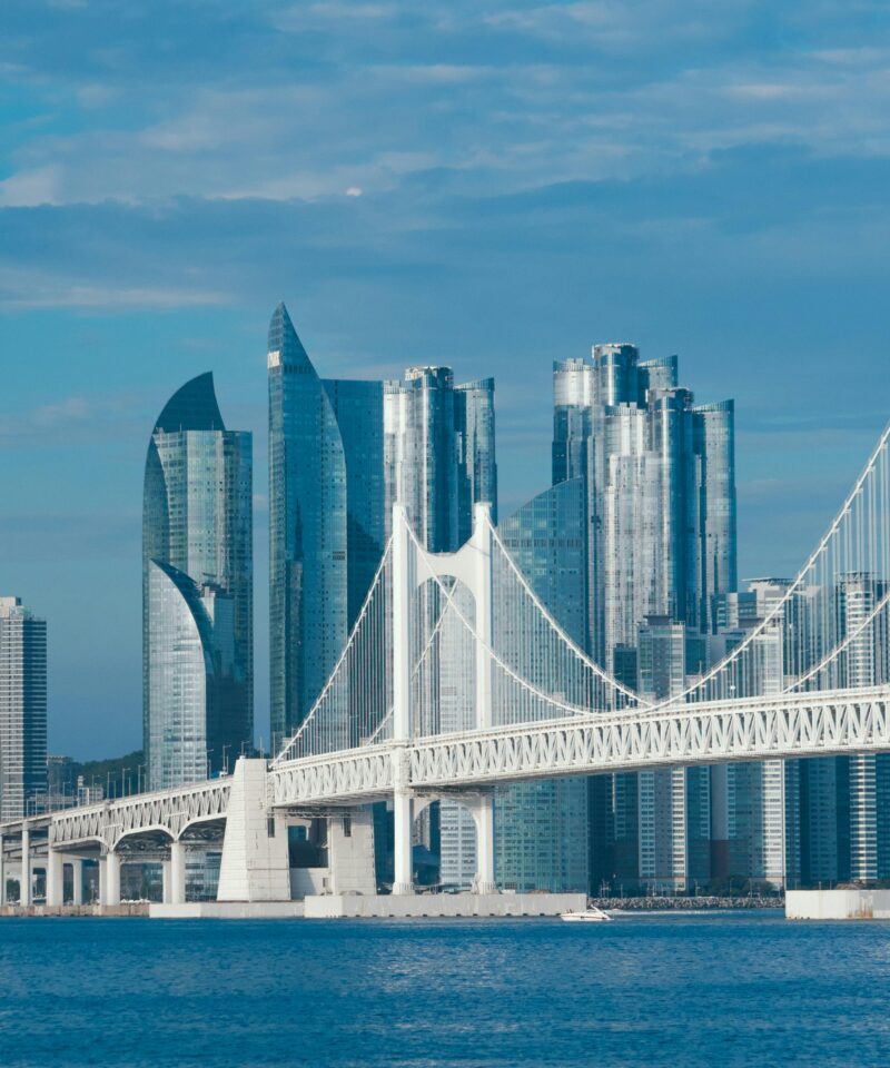 Stunning view of Gwangandaegyo Bridge and Busan skyscrapers under a clear blue sky.