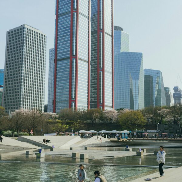 A vibrant view of Seoul skyscrapers with cherry blossoms and people enjoying the park in spring.